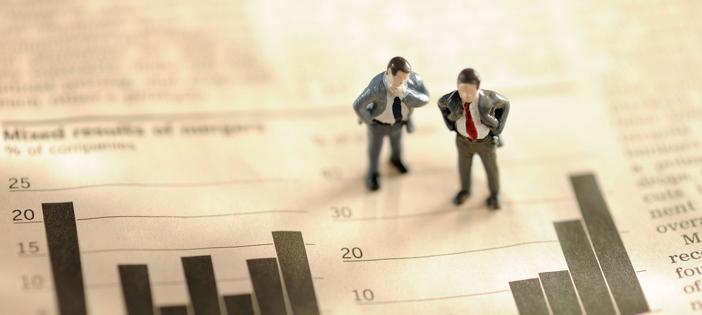 Two figurines examining a stock market graph