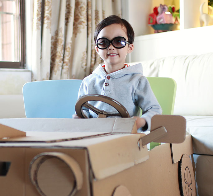A boy behind the wheel of his cardboard box-car