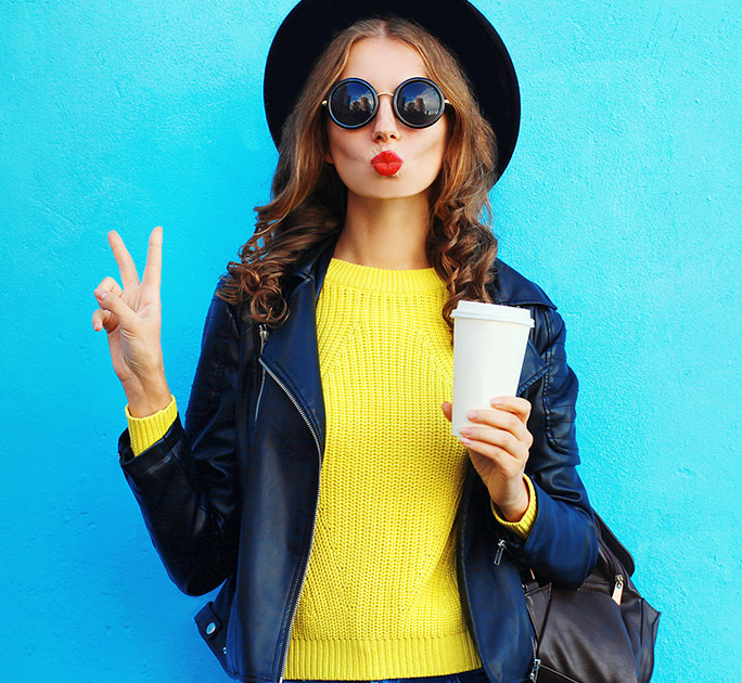 Young female college student posing with a cup of coffee in hand